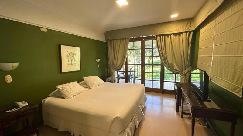 Chambre lumineuse avec un grand lit et un accès à une terrasse.