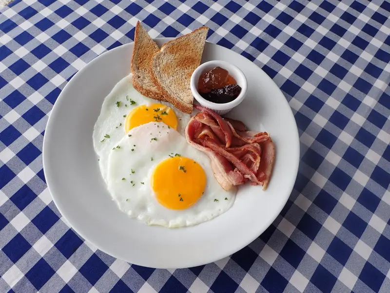 Assiette de petit-déjeuner avec œufs au plat, bacon et toasts.