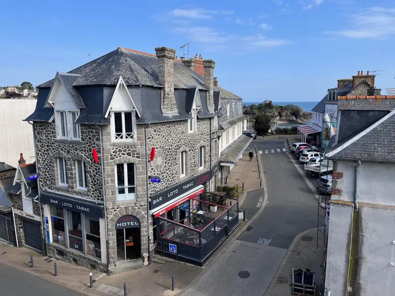 Façade d'un bâtiment avec une terrasse et un commerce au rez-de-chaussée.