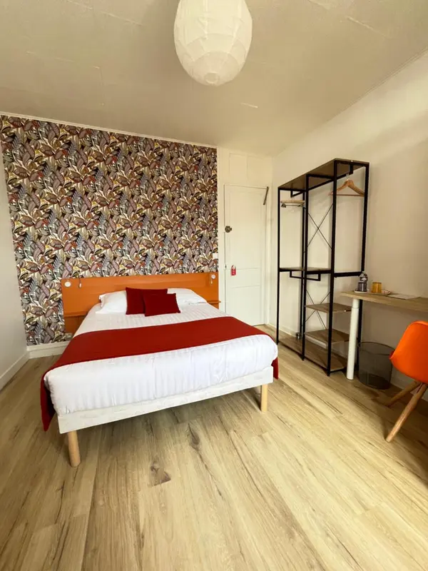 Une chambre lumineuse avec un lit recouvert d'une courtepointe blanche et d'oreillers rouges.