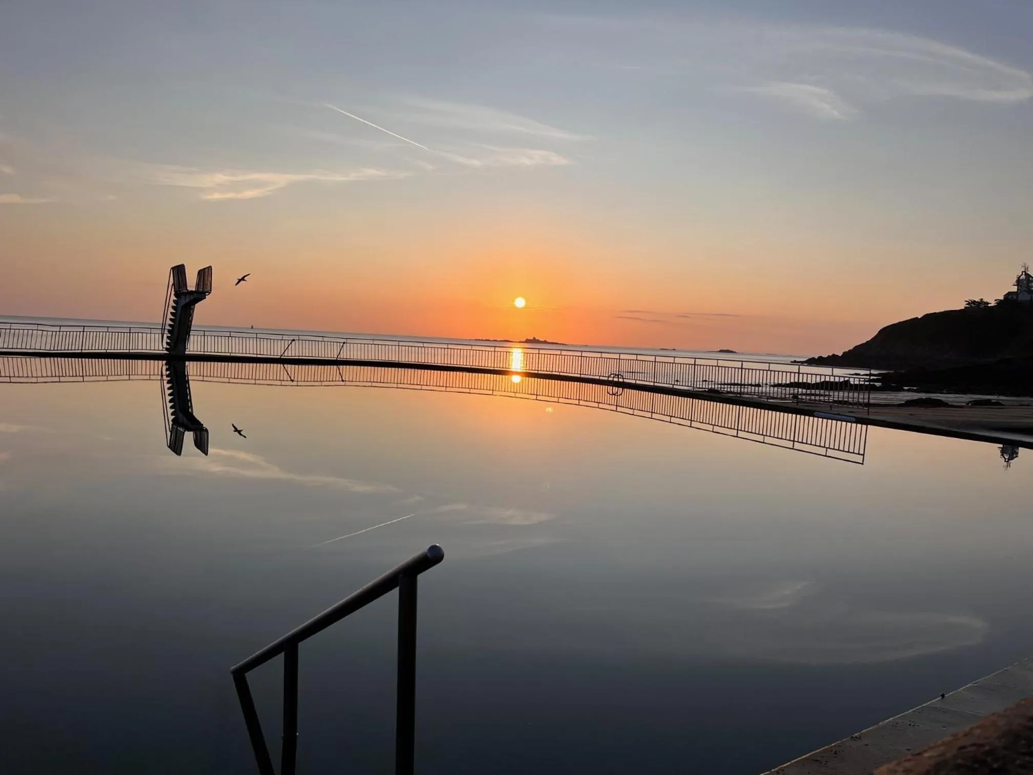 Un coucher de soleil se reflète sur une piscine calme.