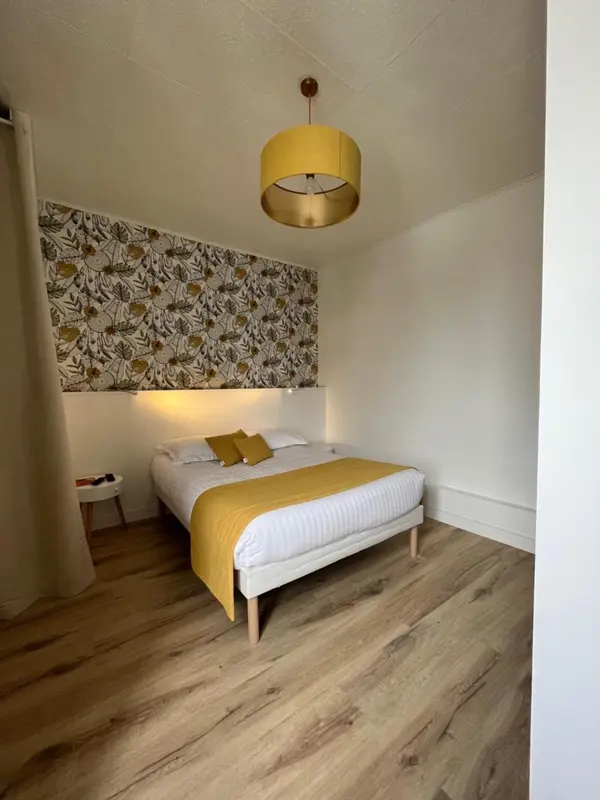 Une chambre lumineuse avec un lit recouvert d'une couverture jaune et d'oreillers assortis.