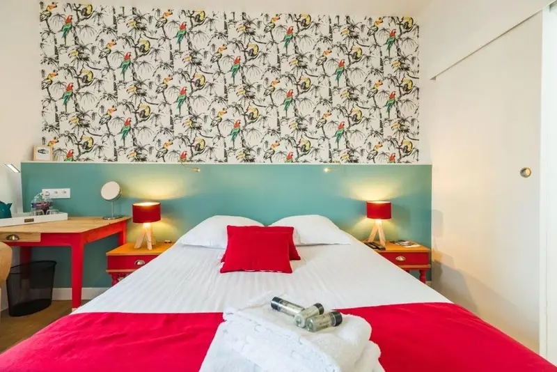 Une chambre lumineuse avec un lit double et un papier peint coloré.
