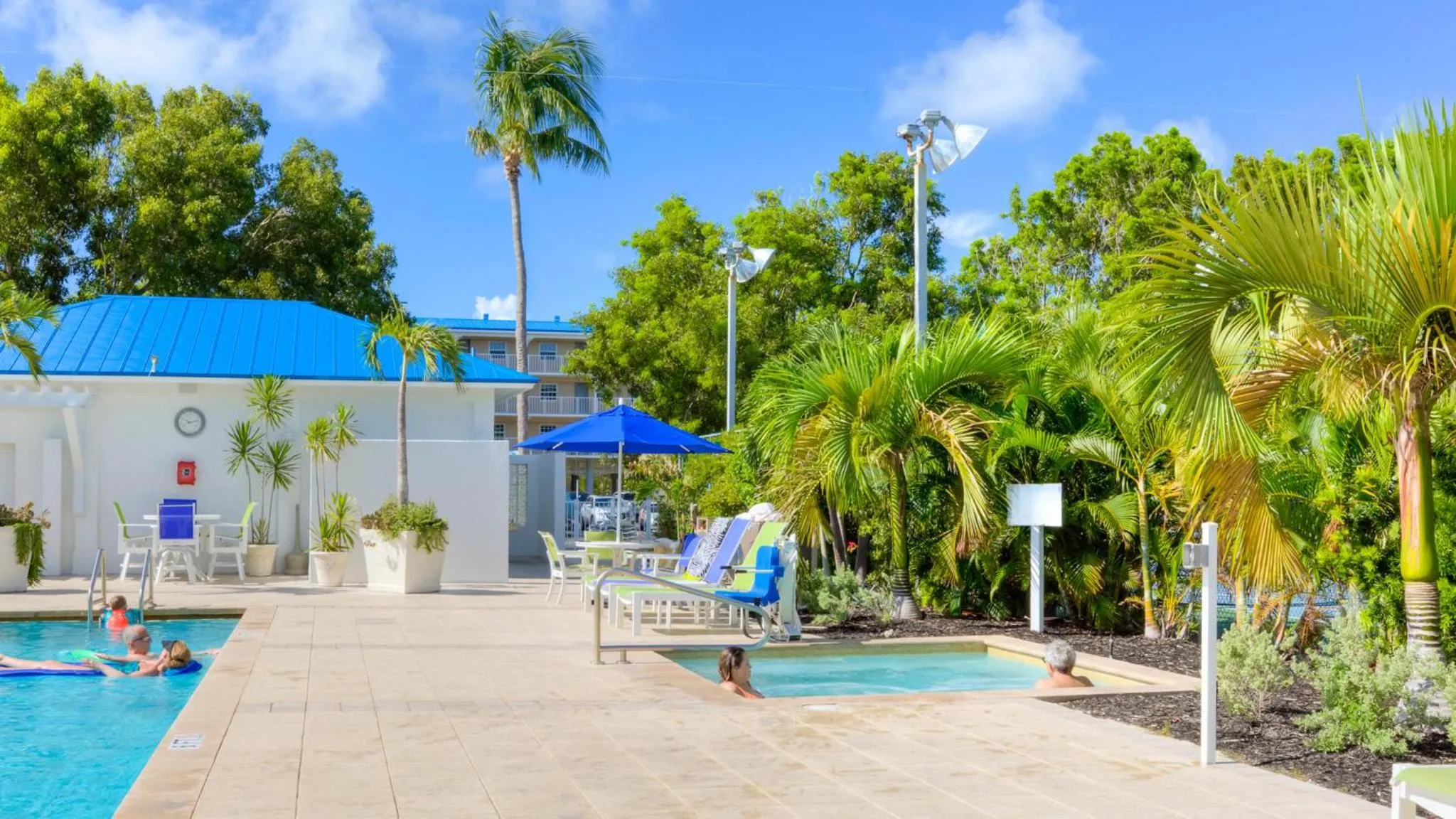 Terrasse avec transats et piscine au milieu d'une végétation tropicale.