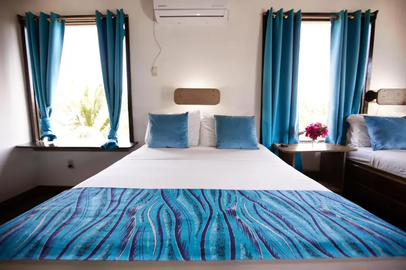 Une chambre lumineuse avec un grand lit recouvert d'une courtepointe bleue et turquoise.