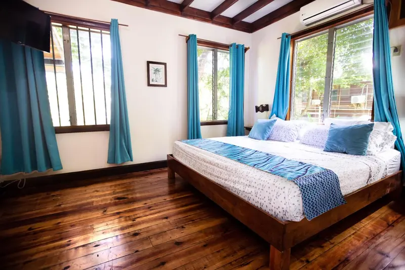 Une chambre lumineuse avec un grand lit et un parquet en bois.