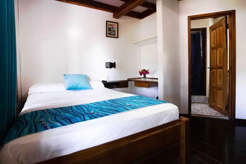 Une chambre lumineuse avec un lit recouvert d'une courtepointe bleue et turquoise.