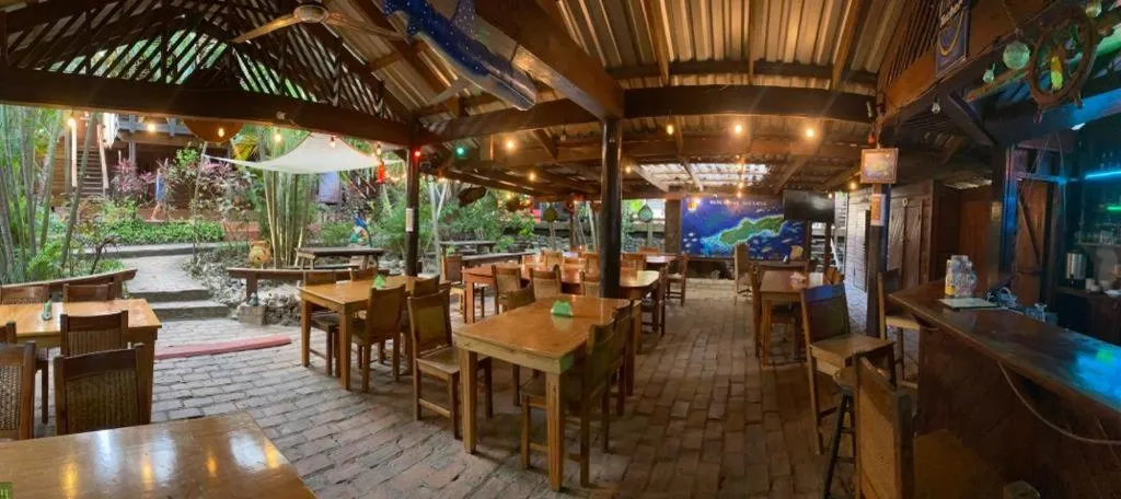 Une salle à manger extérieure abritée sous une toiture en bois et en chaume.