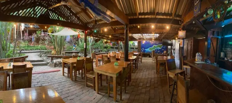 Une salle à manger extérieure abritée sous une toiture en bois et en chaume.