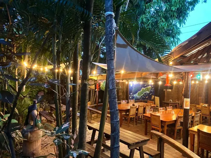 Terrasse ombragée avec tables et chaises en bois.
