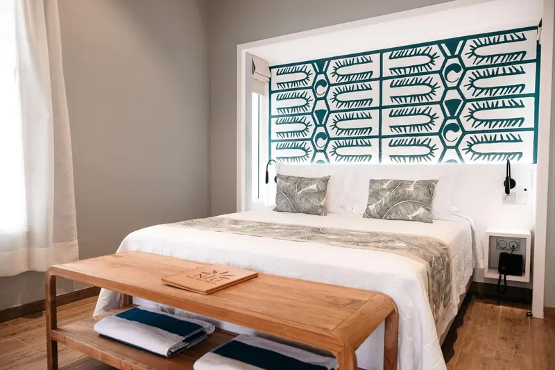 Une chambre lumineuse avec un grand lit et une décoration murale graphique.