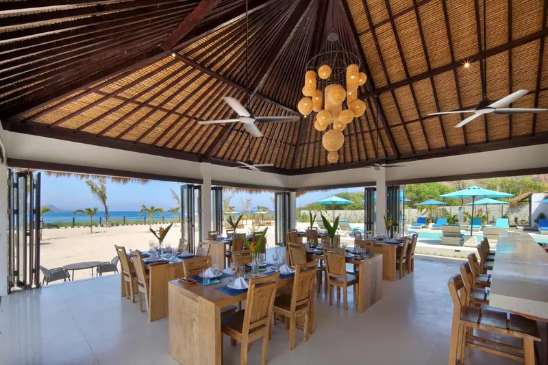 Une salle à manger lumineuse s'ouvre sur une plage de sable fin.