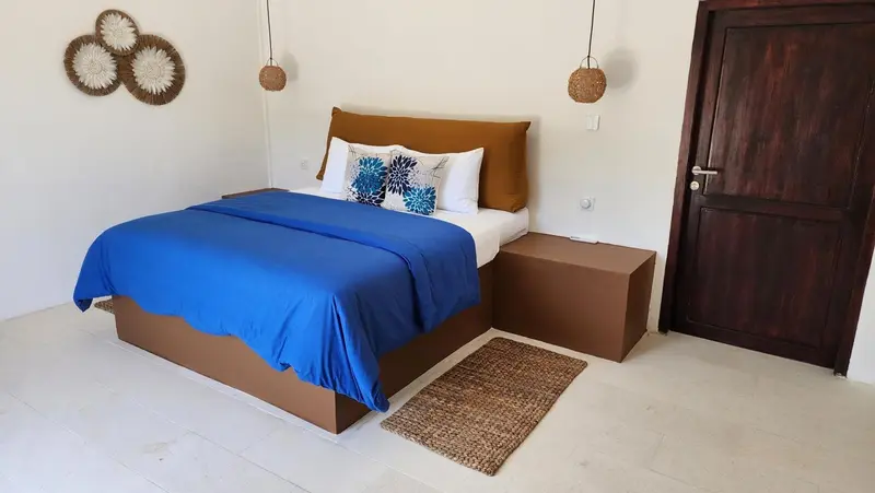 Une chambre lumineuse avec un grand lit recouvert d'une couverture bleue.