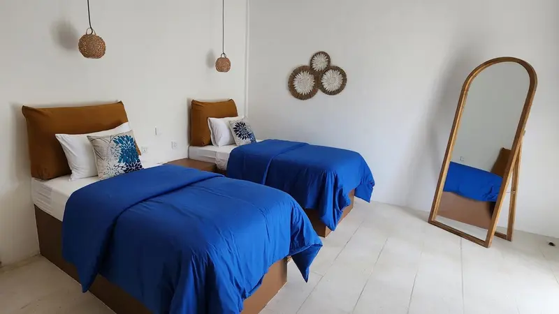 Une chambre lumineuse avec deux lits simples et un grand miroir.