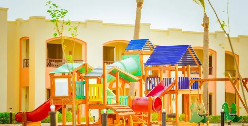 Structure de jeux colorée pour enfants devant un bâtiment jaune.