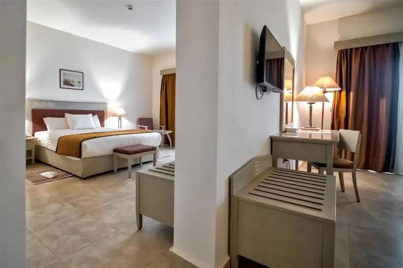 Une chambre lumineuse avec un lit double et un coin salon.