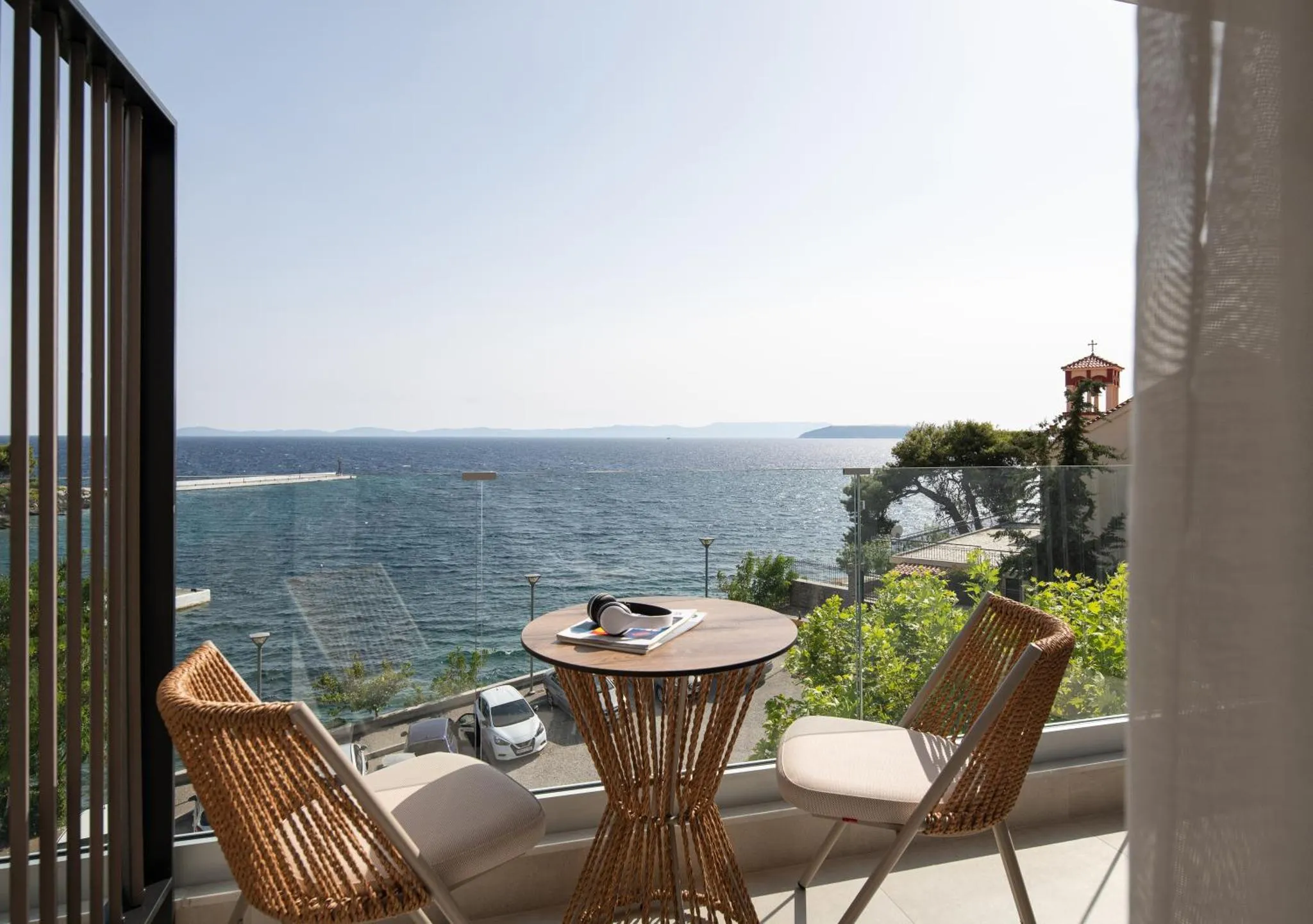 Terrasse avec mobilier en rotin donnant sur la mer et un paysage côtier.
