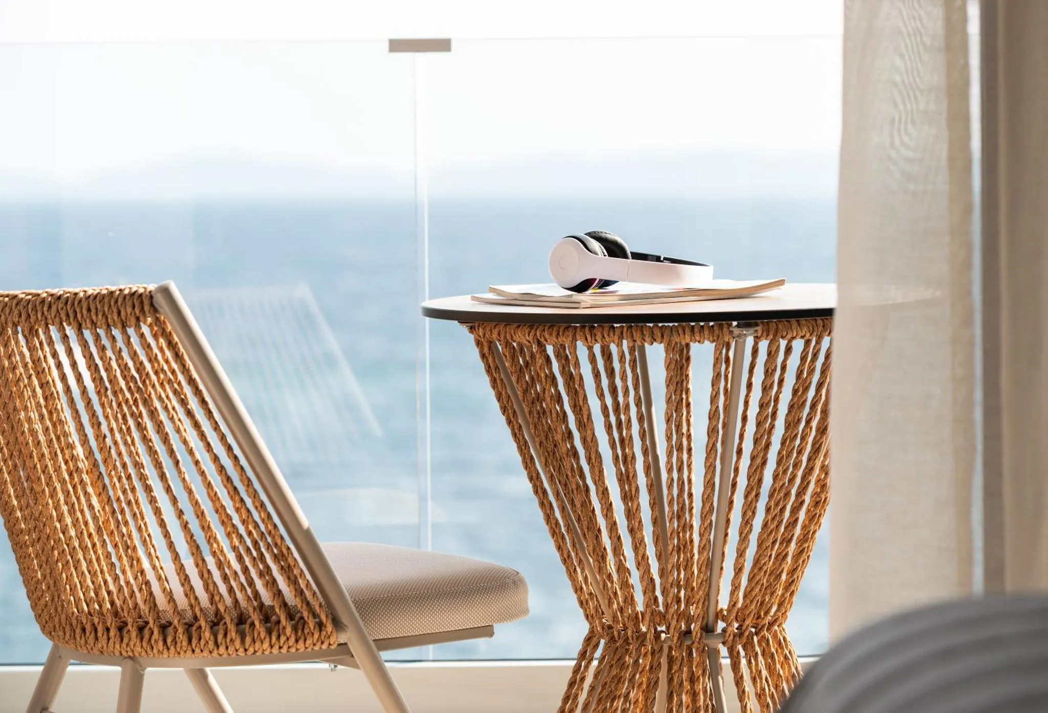 Deux fauteuils en rotin sur une terrasse avec vue sur la mer.