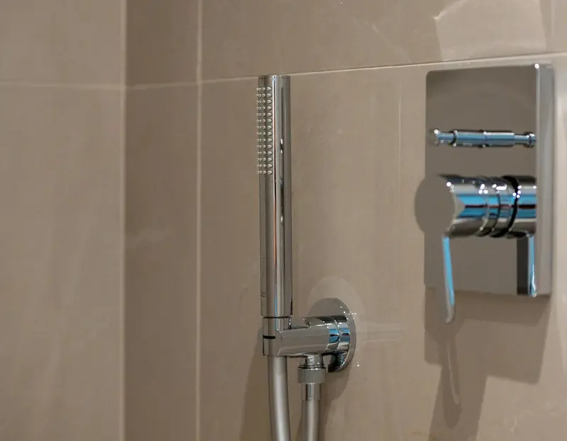 Douche murale chromée avec pommeau et robinetterie.