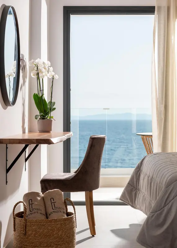 Une chambre lumineuse avec vue sur la mer depuis une grande fenêtre.