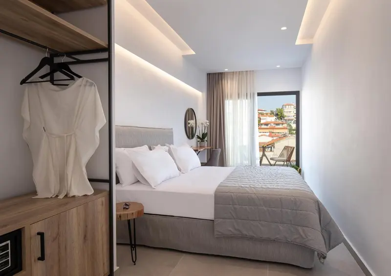 Une chambre lumineuse avec un lit fait et un dressing ouvert.