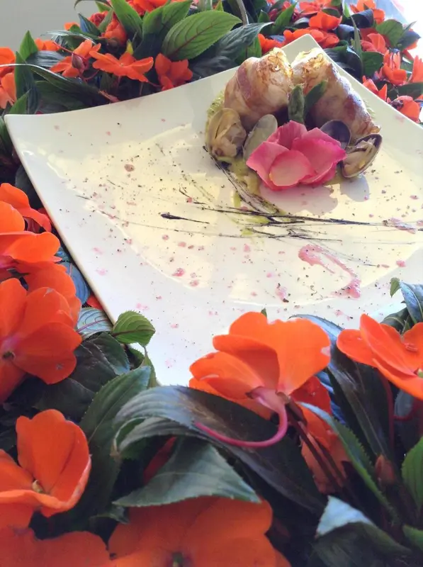 Assiette raffinée ornée de fleurs et d'une préparation culinaire décorée.