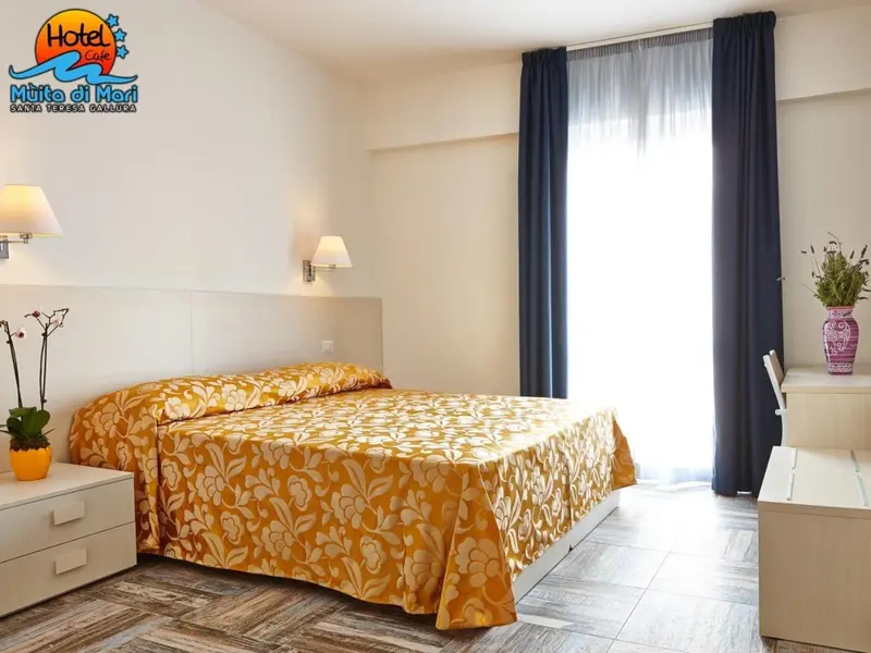 Une chambre lumineuse avec un grand lit recouvert d'une courtepointe à motifs.