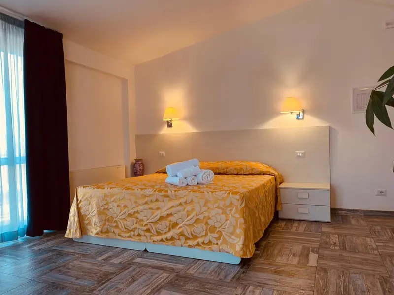 Une chambre lumineuse avec un grand lit recouvert d'une courtepointe jaune.
