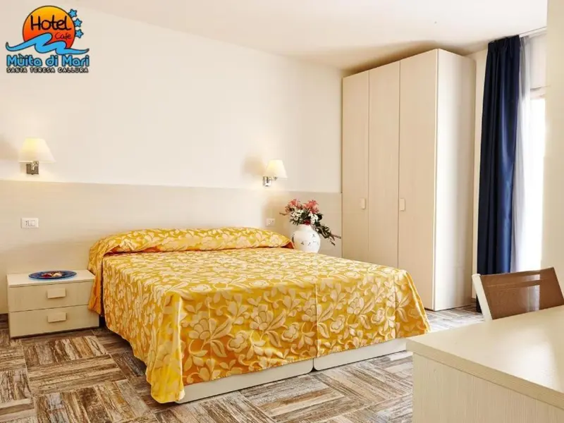 Une chambre lumineuse avec un grand lit recouvert d'une courtepointe à motifs.