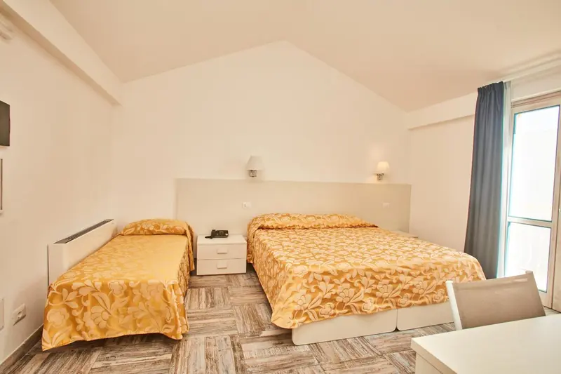 Chambre lumineuse avec deux lits simples et une table de chevet.