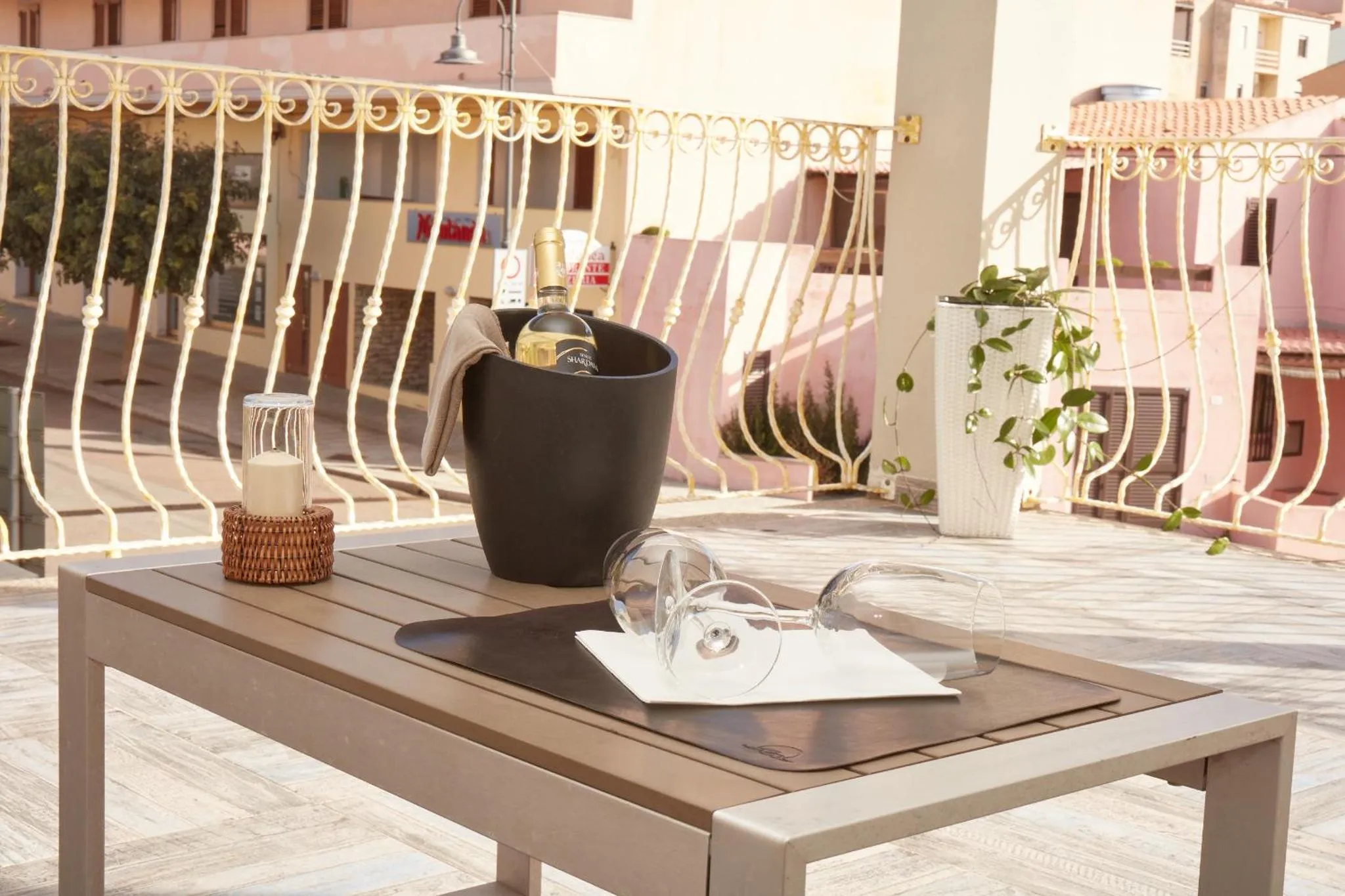 Une table en bois avec des verres et une bouteille sur une terrasse ensoleillée.