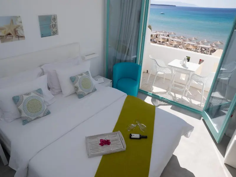 Une chambre lumineuse s'ouvre sur une terrasse avec vue sur la mer.