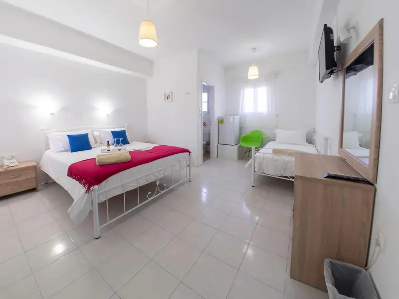 Chambre lumineuse avec deux lits et une commode.
