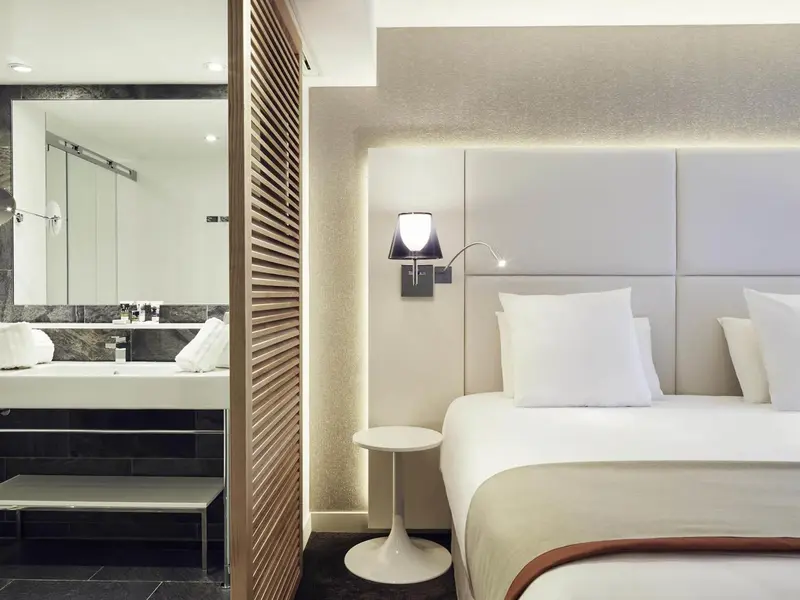 Chambre moderne avec un grand lit et un espace salle de bain attenant.