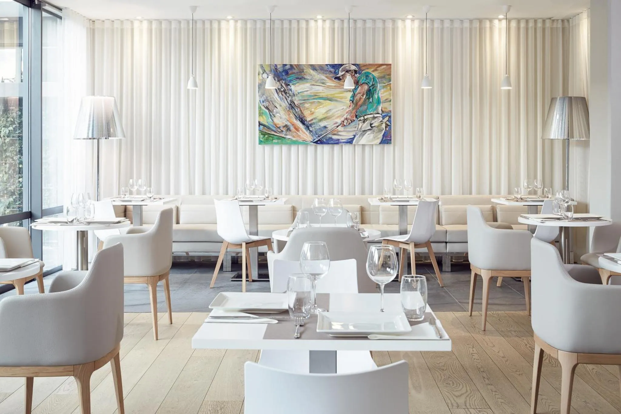 Une salle de restaurant lumineuse avec des tables dressées et une décoration murale abstraite.