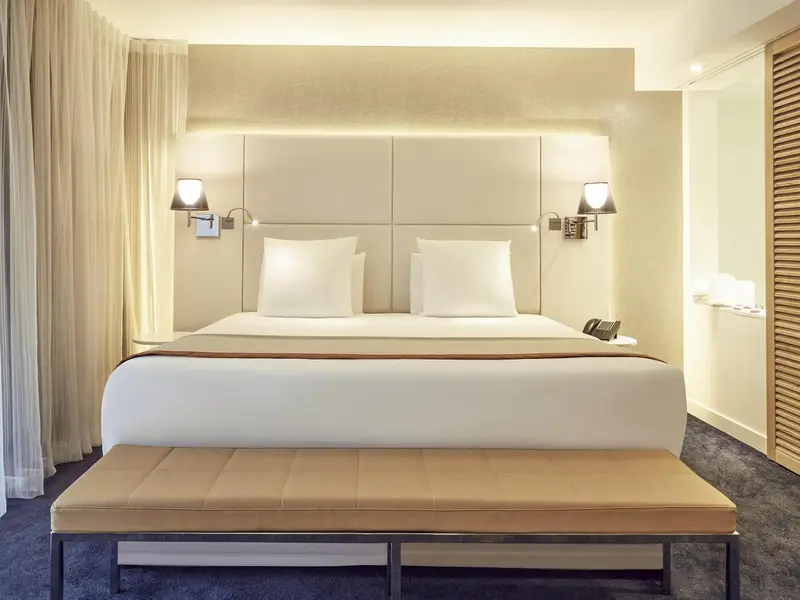 Une chambre lumineuse avec un grand lit et une banquette.