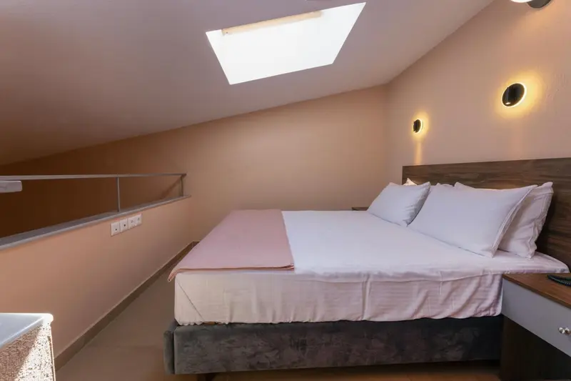 Une chambre mansardée avec un lit double et des tables de chevet.