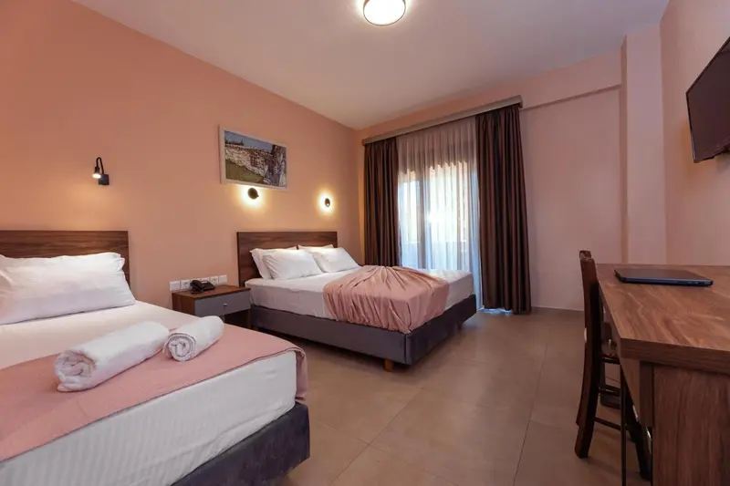 Une chambre d'hôtel lumineuse avec deux lits et un bureau.