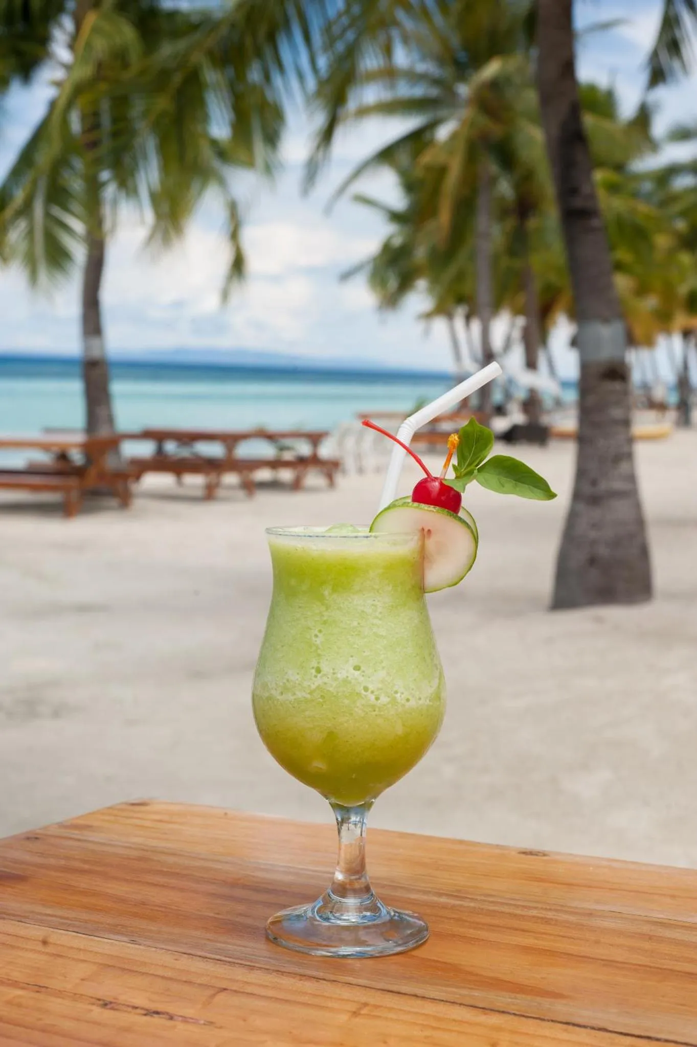Un cocktail exotique est servi sur une table en bois face à la mer.