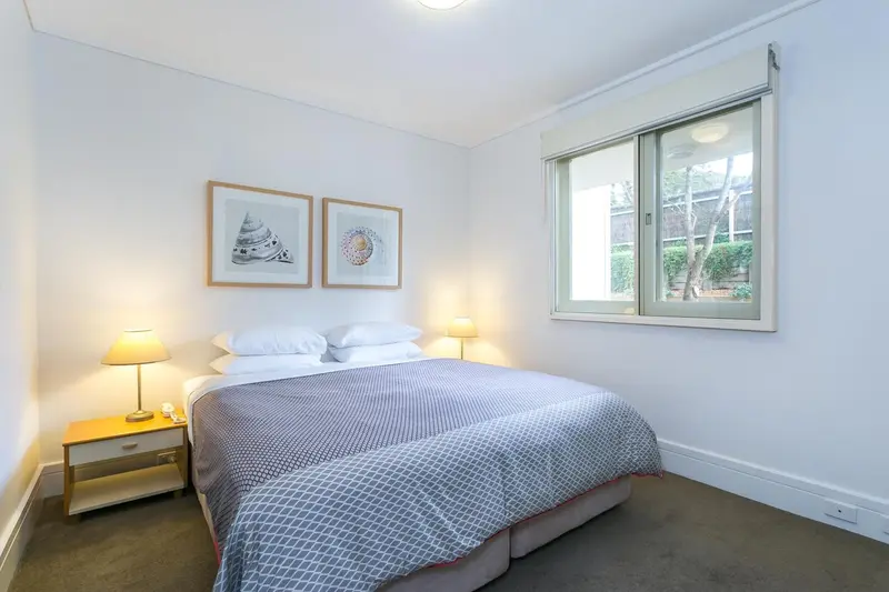 Une chambre lumineuse avec un lit double et deux tableaux décoratifs.