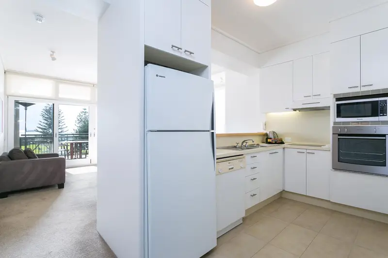 Une cuisine moderne avec un réfrigérateur blanc et des appareils électroménagers intégrés.