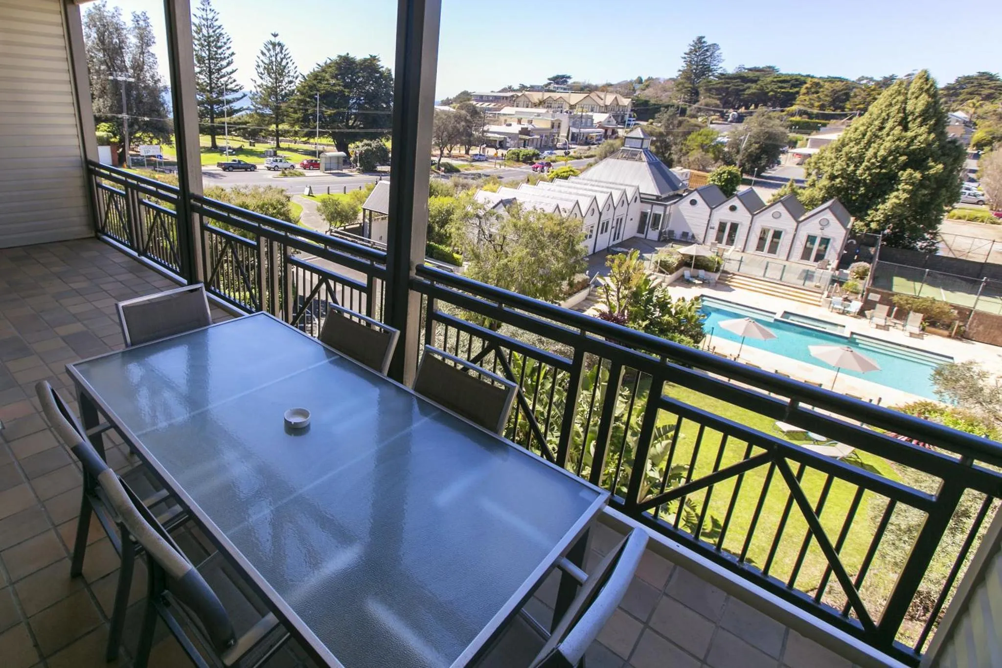 Terrasse avec table et chaises donnant sur un paysage urbain et une piscine.