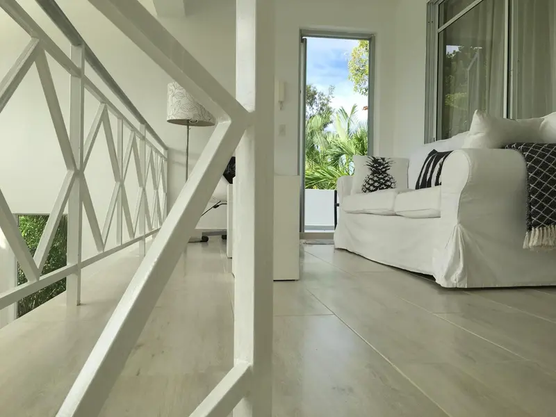Espace de détente lumineux avec canapé blanc et vue sur la végétation.