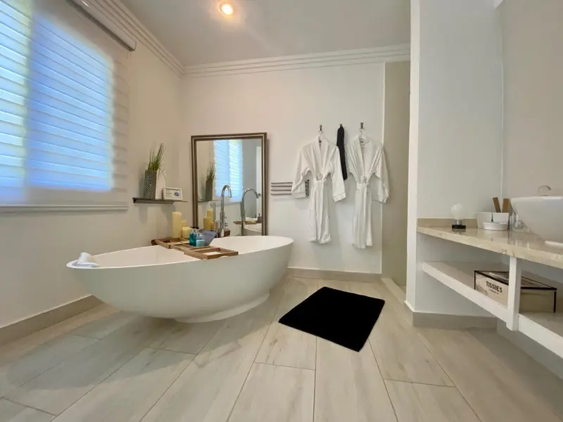 Une salle de bain lumineuse avec une baignoire îlot et des peignoirs blancs.