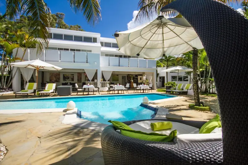 Une piscine turquoise bordée de chaises longues et de parasols blancs invite à la détente.