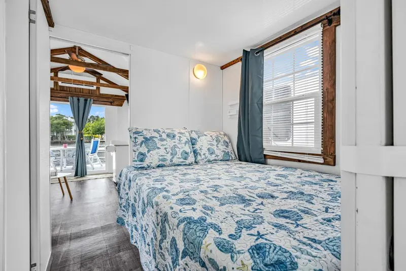 Une chambre lumineuse avec un lit recouvert d'une courtepointe à motifs et une vue sur une terrasse.