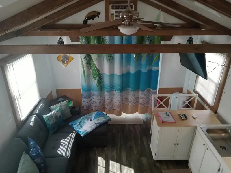 Espace de vie intérieur avec canapé, cuisine et rideaux bleus.