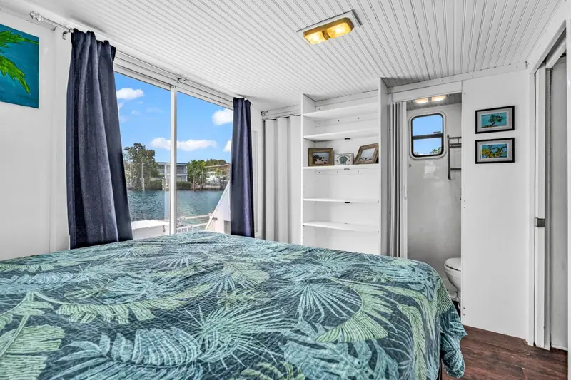 Une chambre lumineuse avec un lit recouvert d'un motif tropical et une vue sur l'eau.