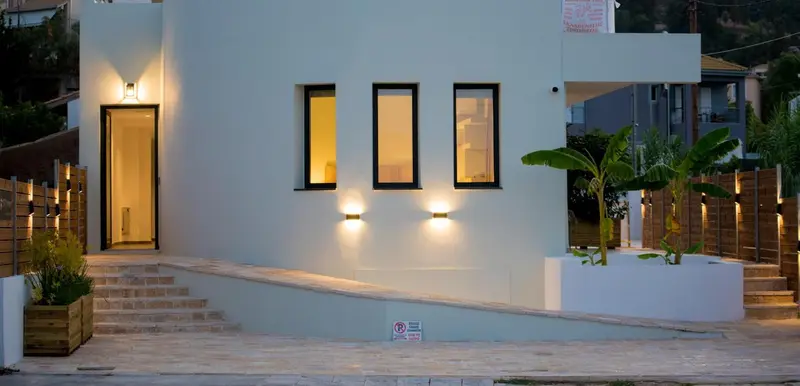 Façade blanche d'un bâtiment avec des fenêtres rectangulaires et un éclairage extérieur.