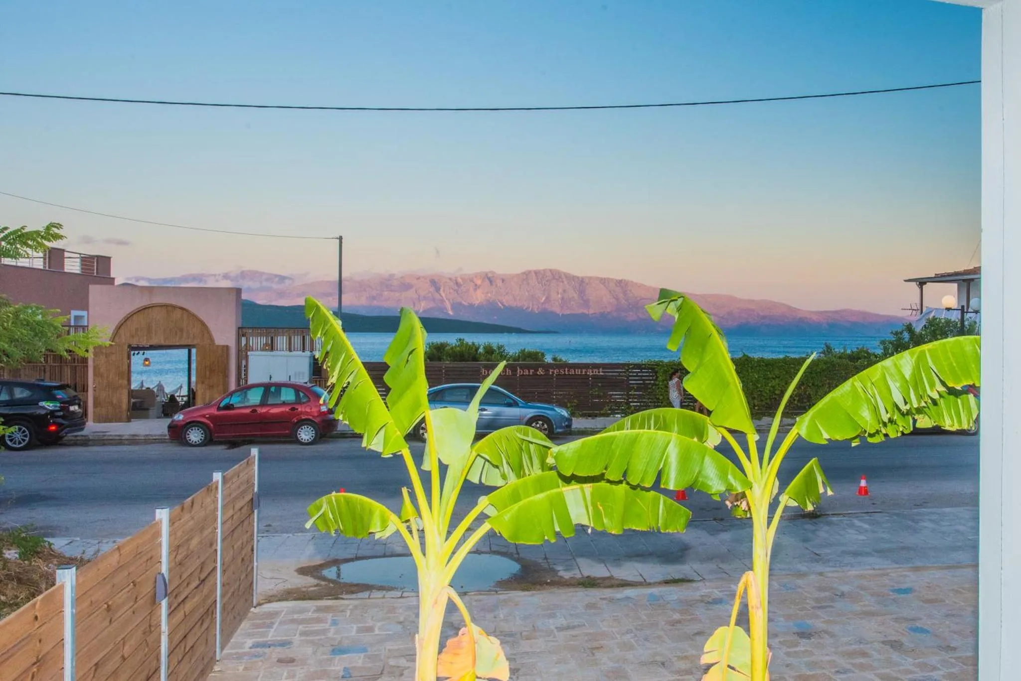 Vue sur la mer et les montagnes depuis une terrasse ensoleillée.